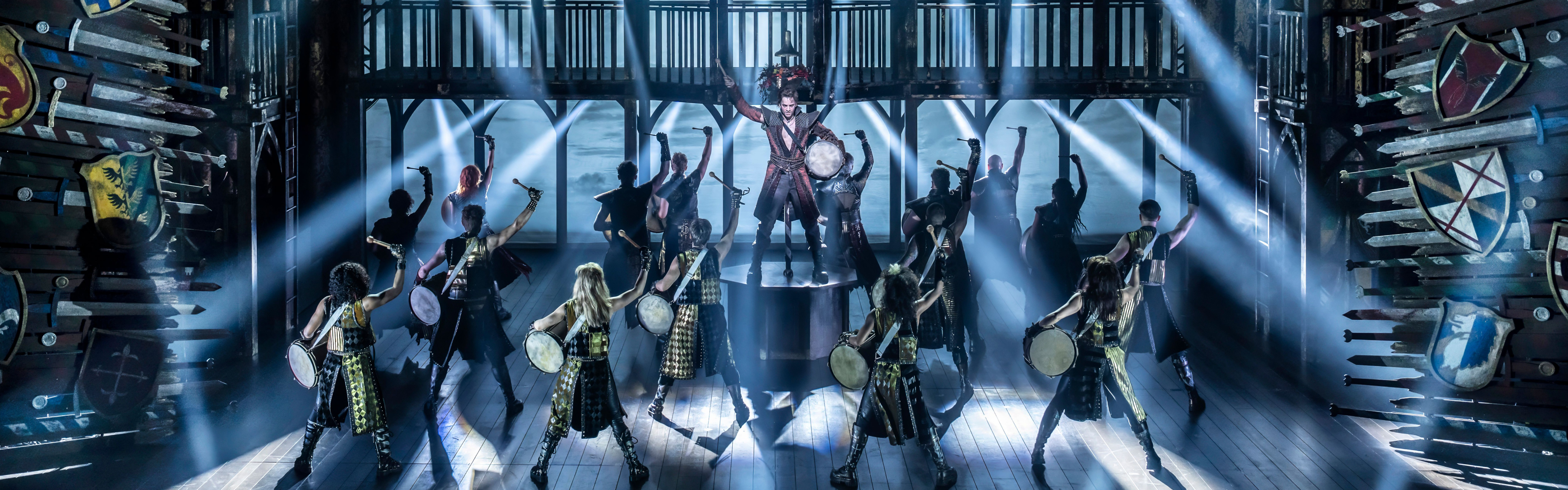 The ensemble of A Knight's Tale dancing with large drums